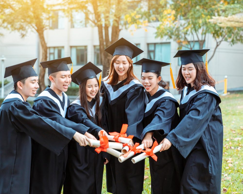 happy students in graduation gowns holding diplomas on universit